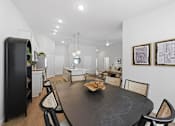 Thumbnail 12 of 26 - A black dining table surrounded by chairs in a white room.