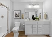 Thumbnail 23 of 26 - A white bathroom with a toilet, sink, and a framed picture on the wall.