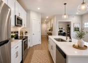 Thumbnail 44 of 47 - A modern kitchen with white cabinets and stainless steel appliances.
