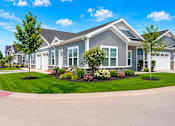 Thumbnail 46 of 47 - A large house with a grey and white exterior and a landscaped front yard.