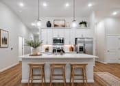 Thumbnail 47 of 47 - A kitchen with white cabinets and a white island with three bar stools.
