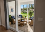 Thumbnail 4 of 47 - A living room with a view of a backyard through a sliding glass door.