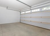 Thumbnail 16 of 33 - A spacious garage with a concrete floor and a white ceiling.