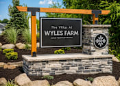 Thumbnail 43 of 47 - A sign for The Villas at Wyles Farm, a luxury apartment complex, is displayed in a landscaped area.