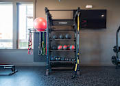 Thumbnail 19 of 31 - A gym with a TRX suspension trainer, a red ball, and a bench.at Eastpark Apartment Homes, Salem, OR