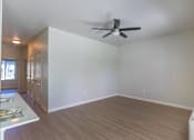 Thumbnail 29 of 51 - A room with a ceiling fan and light fixture, wooden flooring, and a white wall.