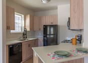 Thumbnail 37 of 51 - A kitchen with a black refrigerator and wooden cabinets.