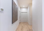 Thumbnail 5 of 82 - A hallway with a wooden floor and white walls.