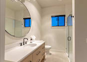 Thumbnail 11 of 82 - A bathroom with a white counter top and a round mirror.