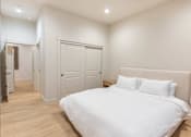 Thumbnail 16 of 82 - A white bed with a white headboard and two white pillows in a bedroom with wooden floors and white walls.