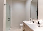 Thumbnail 18 of 82 - A white bathroom with a sink, toilet, and a mirror.