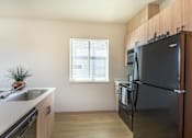Thumbnail 38 of 82 - A kitchen with a black fridge and a window.