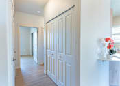 Thumbnail 56 of 82 - A hallway with white doors and a vase of flowers on a ledge.
