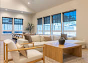 Thumbnail 10 of 82 - A living room with a white couch, a wooden coffee table, and a chair with a wooden frame.