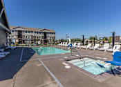 Thumbnail 10 of 51 - A large outdoor swimming pool with lounge chairs and a building in the background at Cascade Place Apartment Homes, Oregon