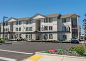 Thumbnail 11 of 51 - A large white building with a red stripe on the side at Cascade Place Apartment Homes, Molalla