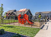 Thumbnail 17 of 51 - A playground with a red slide is in front of a building at Cascade Place Apartment Homes, Molalla, 97038