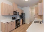 Thumbnail 19 of 51 - A kitchen with wooden cabinets and black appliances at Cascade Place Apartment Homes, Molalla, Oregon