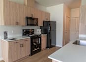 Thumbnail 27 of 51 - A kitchen with wooden cabinets and black appliances at Cascade Place Apartment Homes, Molalla