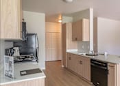 Thumbnail 28 of 51 - A kitchen with wooden cabinets and a black stove top at Cascade Place Apartment Homes, Molalla, OR, 97038