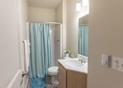 Thumbnail 34 of 51 - A bathroom with a toilet, sink, and shower curtain at Cascade Place Apartment Homes, Molalla, Oregon