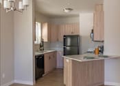 Thumbnail 36 of 51 - A kitchen with wooden cabinets and a black refrigerator at Cascade Place Apartment Homes, Oregon