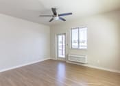 Thumbnail 38 of 51 - A room with a ceiling fan and a window with a view of a balcony at Cascade Place Apartment Homes, Molalla