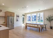 Thumbnail 4 of 51 - A kitchen with a refrigerator, a table and chairs, and a potted plant at Cascade Place Apartment Homes, Molalla, Oregon