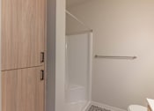Thumbnail 40 of 51 - A white toilet sits in a small bathroom with a walk-in shower at Cascade Place Apartment Homes, Molalla