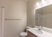 Thumbnail 41 of 51 - A white toilet sits next to a sink in a small bathroom at Cascade Place Apartment Homes, Molalla