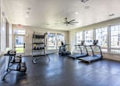Thumbnail 5 of 51 - A spacious gym with treadmills, weights, and a ceiling fan at Cascade Place Apartment Homes, Molalla, OR