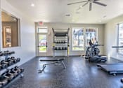 Thumbnail 7 of 51 - A gym with a treadmill, weights, and a bench at Cascade Place Apartment Homes, Molalla, Oregon