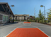 Thumbnail 1 of 36 - A basketball court with a red surface and white lines at Forestplace Apartment Homes, Forest Grove