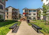 Thumbnail 10 of 36 - A sunny day at a residential area with apartment buildings and benches at Forestplace Apartment Homes, Oregon, 97116