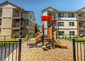 Thumbnail 12 of 36 - A playground with a slide and a wooden platform is in front of a building at Forestplace Apartment Homes, Forest Grove, 97116