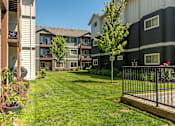 Thumbnail 13 of 36 - A black and white apartment building with a green lawn in front at Forestplace Apartment Homes, Forest Grove, OR, 97116