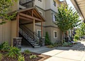 Thumbnail 14 of 36 - A building with a wooden porch and a staircase leading to the entrance at Forestplace Apartment Homes, Forest Grove, OR
