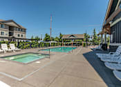 Thumbnail 18 of 36 - A large outdoor swimming pool with lounge chairs and a gazebo at Forestplace Apartment Homes, Forest Grove, Oregon