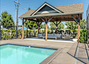 Thumbnail 22 of 36 - A pool with a brown roofed pavilion at Forestplace Apartment Homes, Forest Grove, OR, 97116