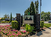 Thumbnail 23 of 36 - A sign for Forest Springs Estates is surrounded by flowers and greenery at Forestplace Apartment Homes, Forest Grove, OR
