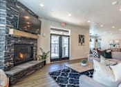 Thumbnail 26 of 36 - A modern living room with a stone fireplace and a flat screen TV mounted above it at Forestplace Apartment Homes, Oregon, 97116