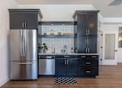Thumbnail 28 of 36 - A kitchen with a stainless steel refrigerator and black cabinets at Forestplace Apartment Homes, Forest Grove