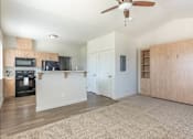 Thumbnail 31 of 36 - A living room with a ceiling fan and a kitchen area with a microwave and oven at Forestplace Apartment Homes, Forest Grove, OR