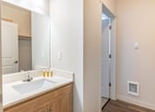 Thumbnail 32 of 36 - A bathroom with a sink, mirror, and a door at Forestplace Apartment Homes, Forest Grove, Oregon