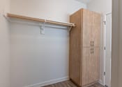 Thumbnail 36 of 36 - A room with a white wall and a wooden cabinet with a shelf above it at Forestplace Apartment Homes, Forest Grove, 97116