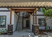 Thumbnail 7 of 36 - A white house with a brown roof and a wooden porch at Forestplace Apartment Homes, Oregon