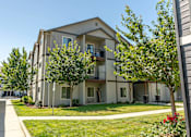 Thumbnail 8 of 36 - Apartment building with green trees and bushes in front at Forestplace Apartment Homes, Forest Grove, Oregon