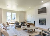 Thumbnail 13 of 25 - A living room with a grey couch, a wooden coffee table, and a television mounted on the wall at Northplace Apartment Homes, Oregon, 97305