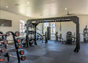 Thumbnail 15 of 25 - A gym with a variety of equipment including a squat rack, bench press, and a pull up bar at Northplace Apartment Homes, Salem, OR, 97305