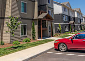 Thumbnail 23 of 25 - A red car is parked in a parking lot in front of a building at Northplace Apartment Homes, Salem